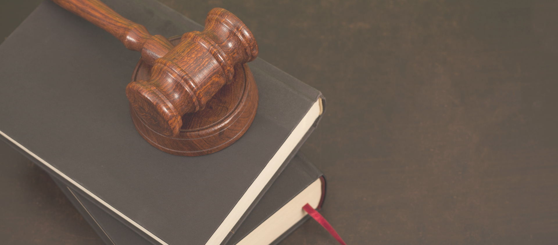 A person signing a document with a gavel in the foreground